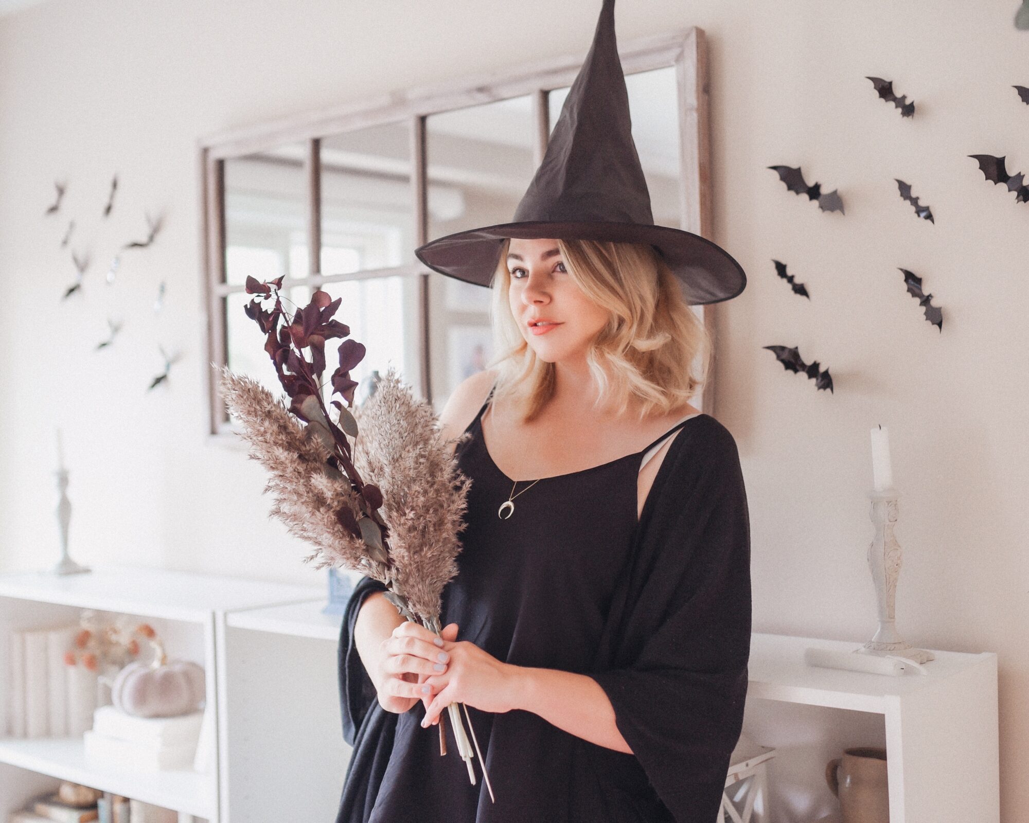 Woman dressed in a witch costume holding dried flowers